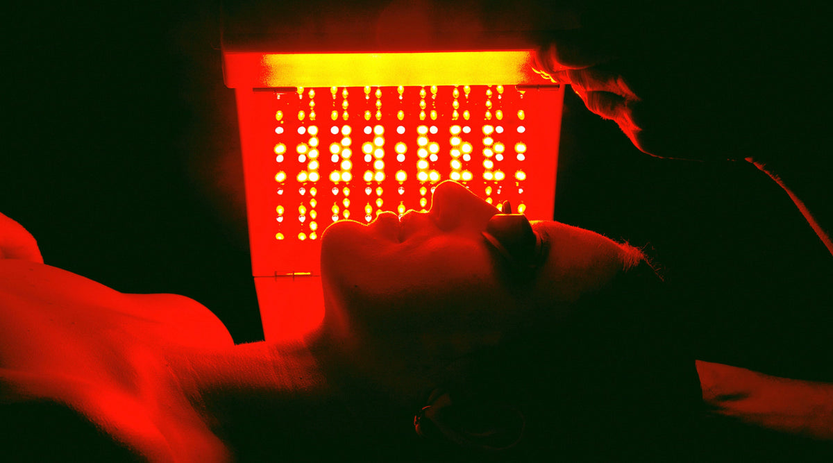 Dark image of woman under the light of an Elipsa treatment given to the face.