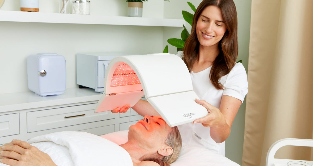 Esthetician providing an elipsa treatment to a client laying on a treatment bed.