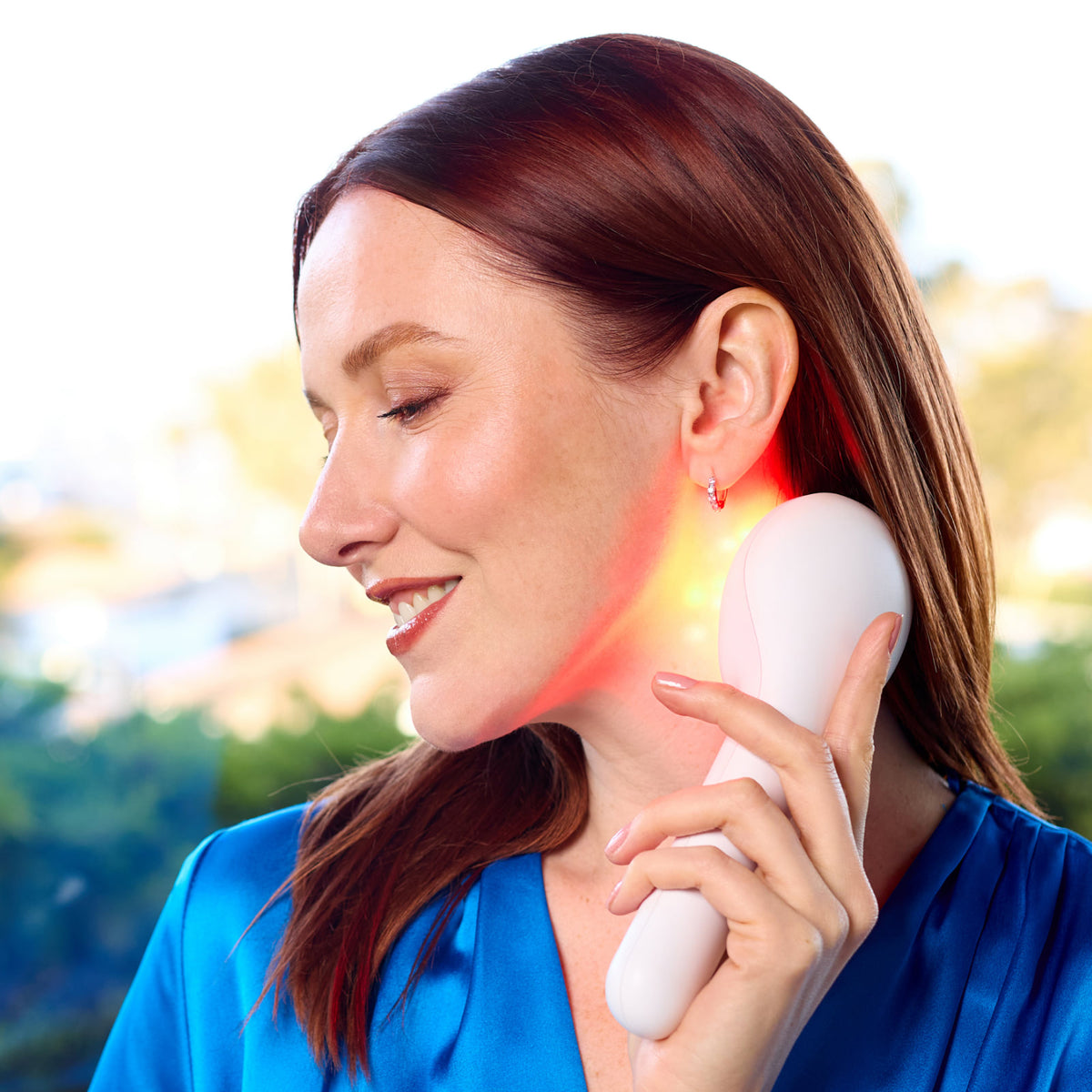 Woman holding a LightStim handheld at her jaw