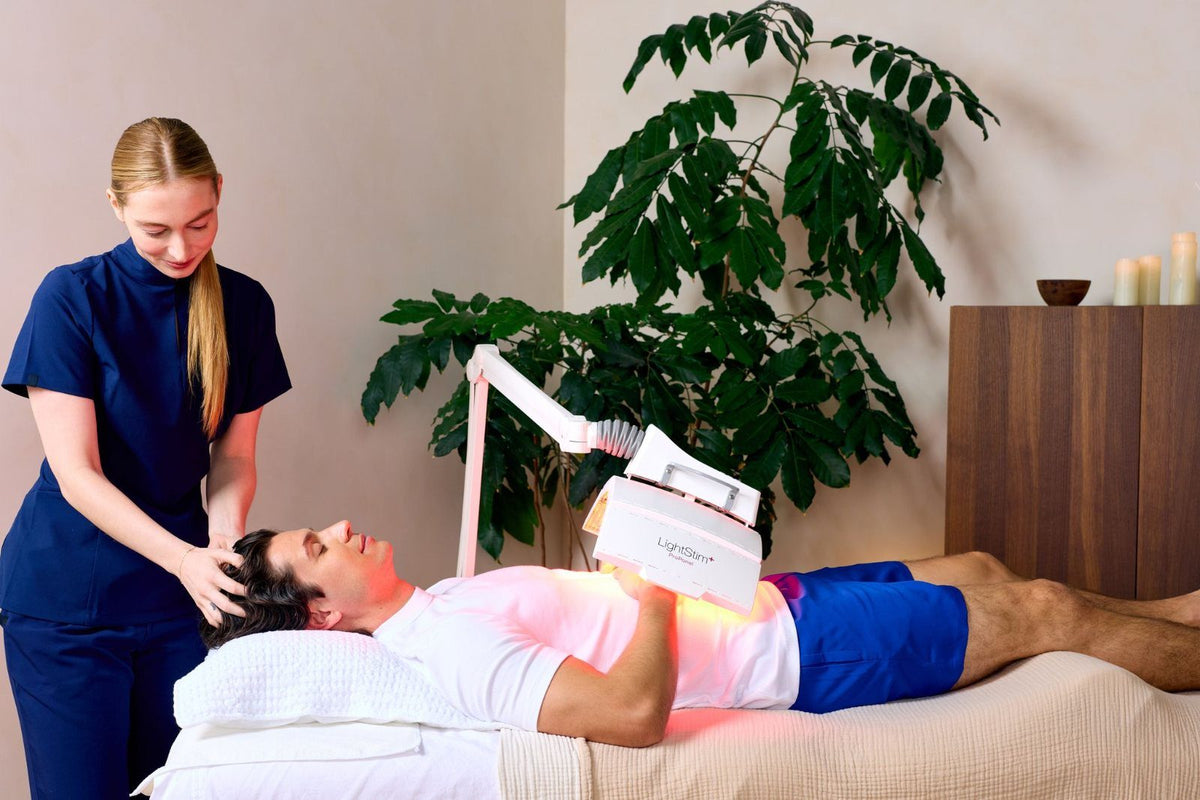 Esthetician giving a scalp massage while a ProPanel shines on the client